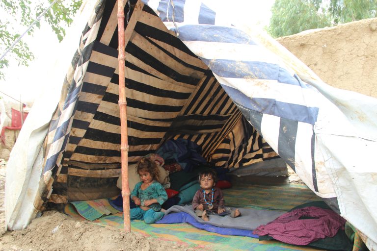 Two young Pakistani girls seek shade from the sun in their make-shift tent.
