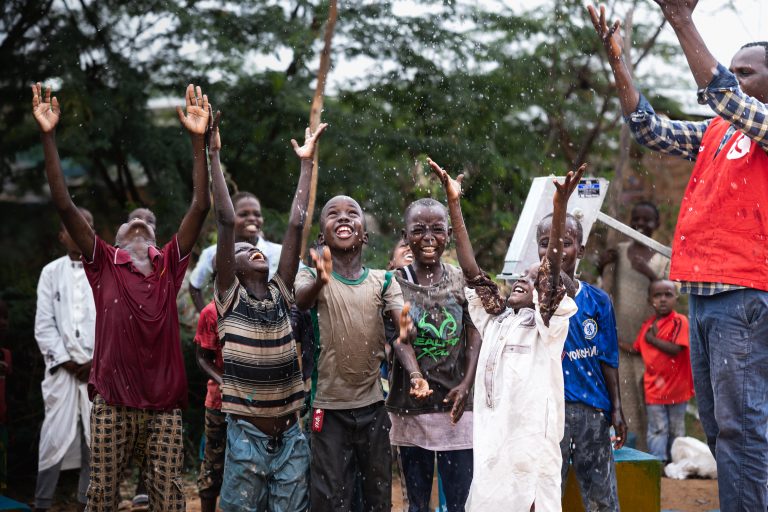 Children from Africa rejoice as they are splashed by water from their new water facility.