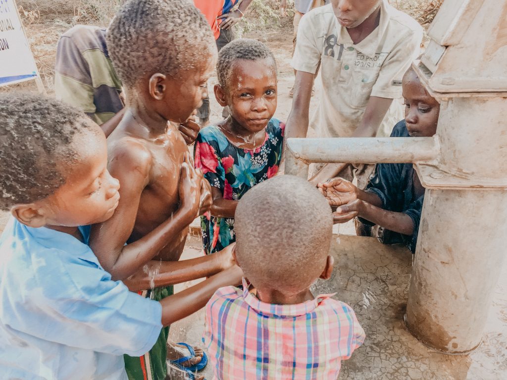Children in Africa rejoice as they retrieve water from a newly installed water pump.