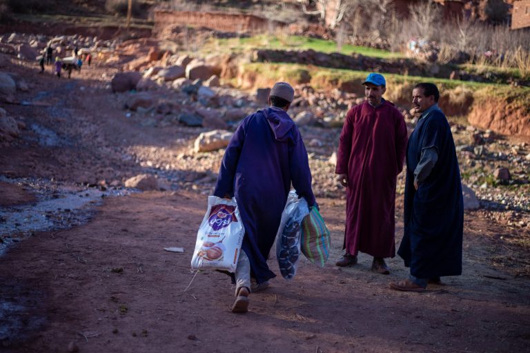 Moroccan men carrying essential aid parcels during winter months.